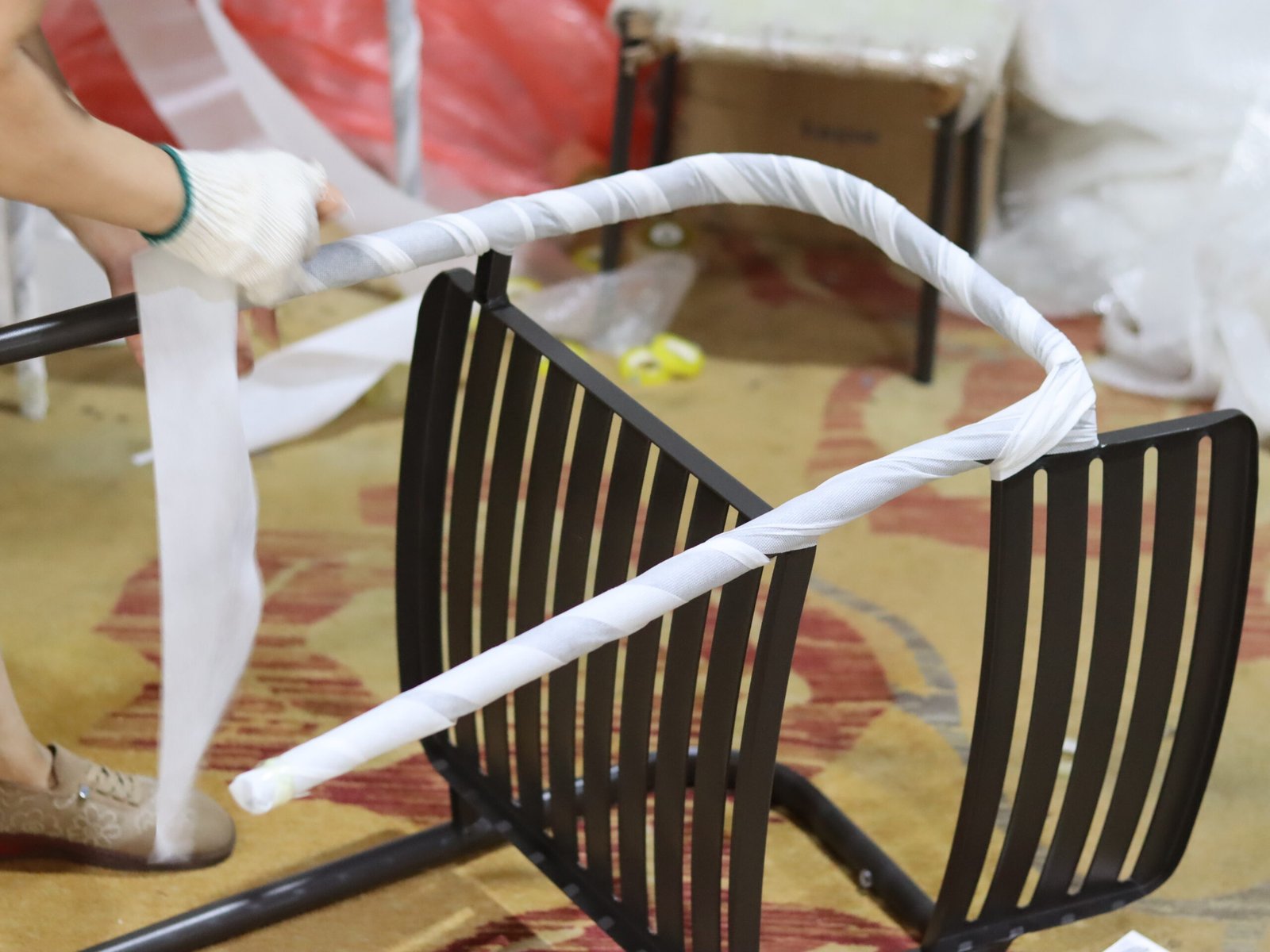 Worker wrapping a metal outdoor chair frame for protective packing