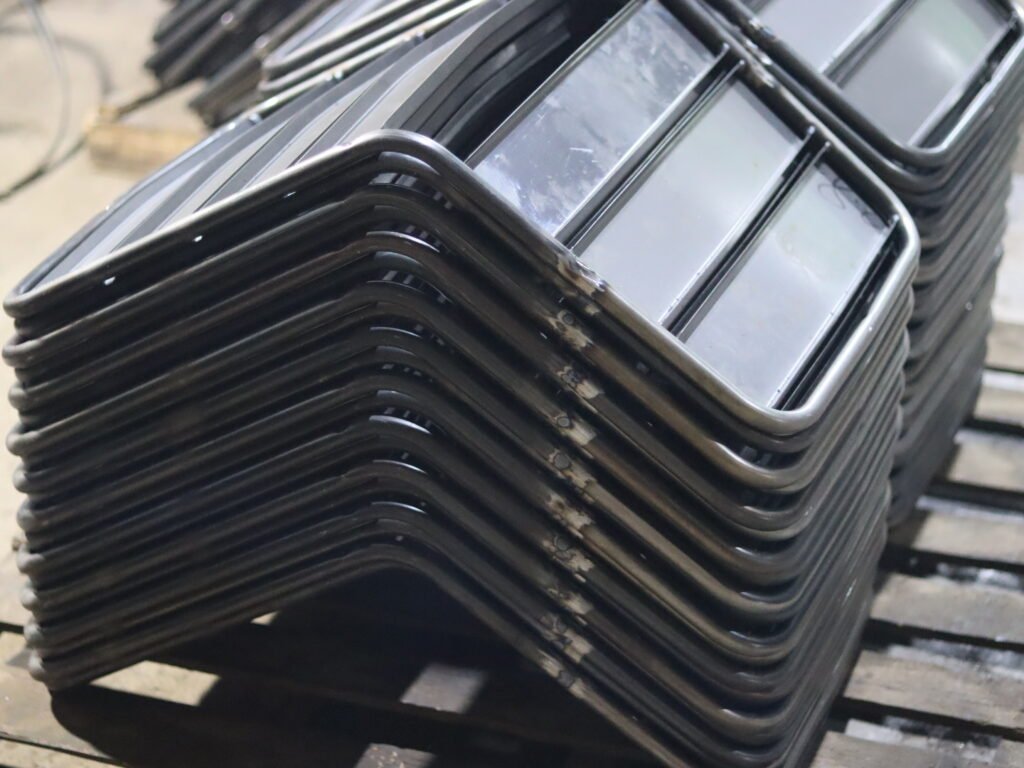Stacked metal chair frames during outdoor furniture manufacturing