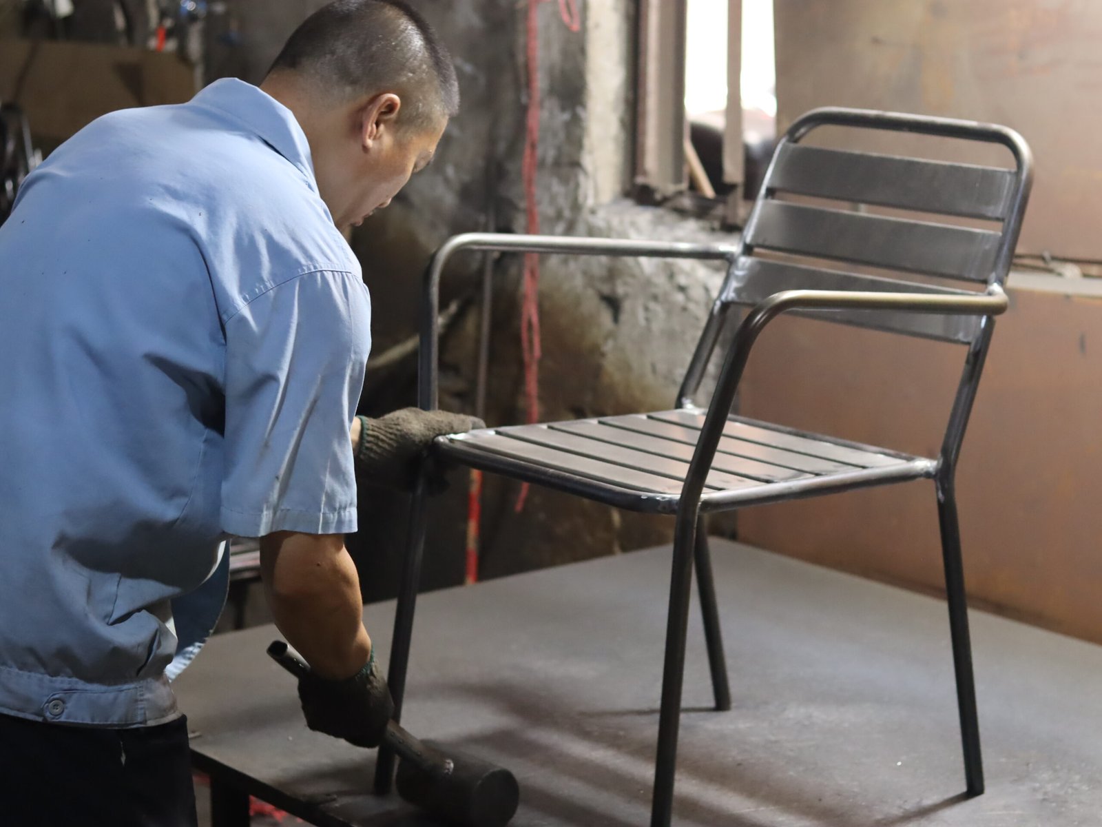 Factory worker checking a finished metal outdoor chair frame